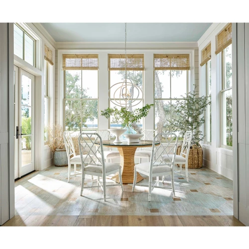 White Sail Chandelier above a round glass dining table with white chairs in a bright room.