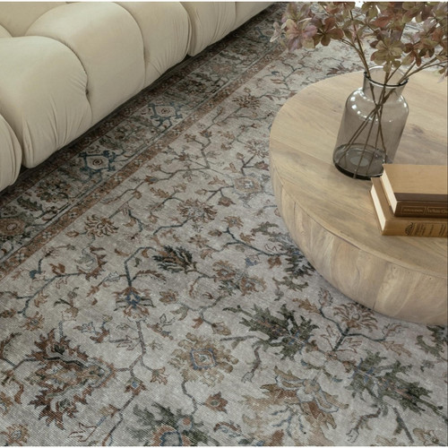 Ivory & multi-color washable polyester rug with distressed traditional patterns, next to a cream sofa and wood coffee table.