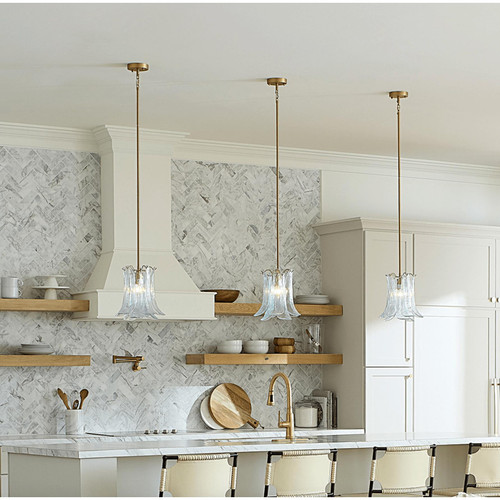 Three Cala light blue blown glass pendant lights with antique brass rods illuminate a modern kitchen island.