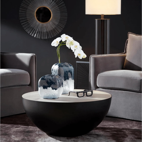 Antiqued silver leaf sunburst mirror with radiating iron lines, above a coffee table with vases and orchids.