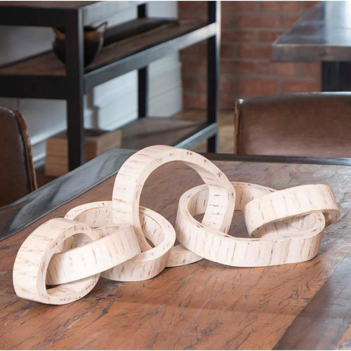 White hand-carved acacia wood links centerpiece on a rustic table.