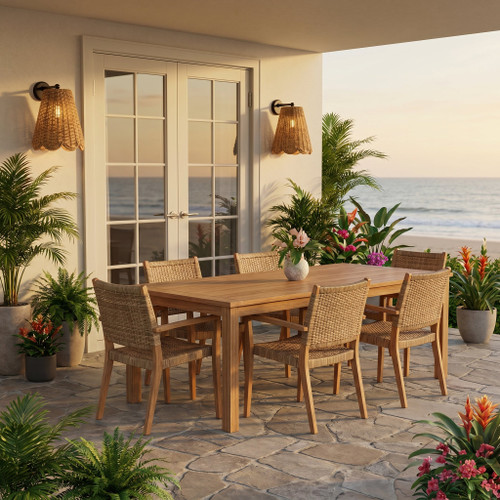 Woven rattan outdoor sconces illuminate a patio with a wooden dining set and ocean view at sunset.