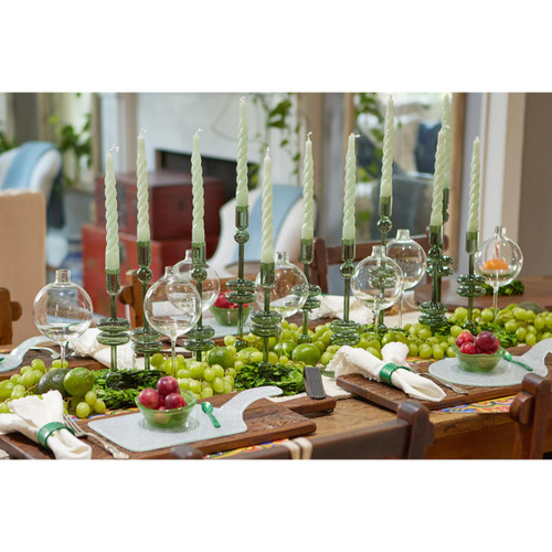 Clear glass sphere vase on a table with green grapes, limes, and red berries.