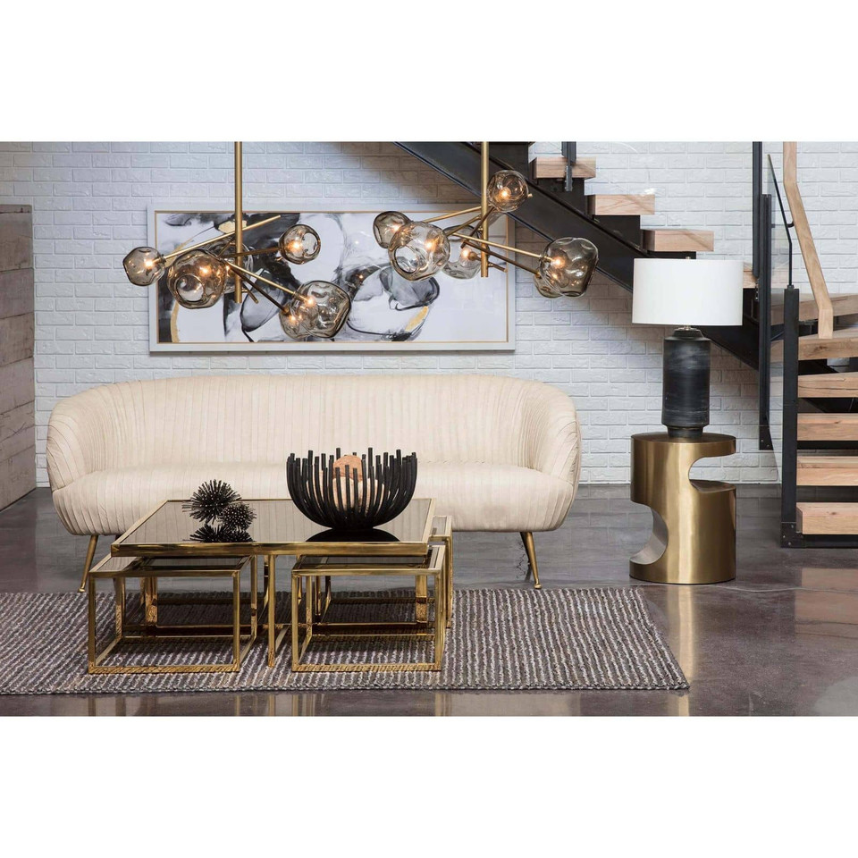 Nathan brass side table with sculptural curves, next to a cream sofa.