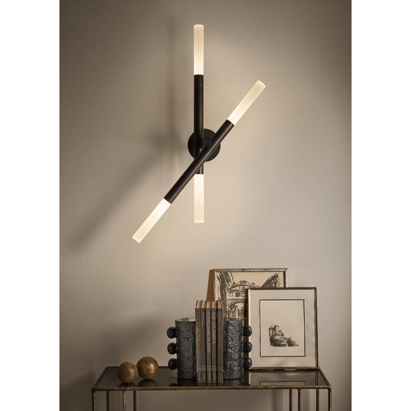 Modern black Cass Wall Sconce with four rotating arms and frosted acrylic diffusers, illuminating a dark room.