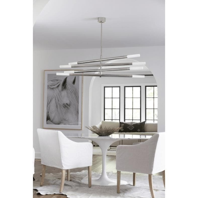 Modern Wick Chandelier in polished nickel with four swiveling arms and frosted acrylic bulb covers over a dining table.