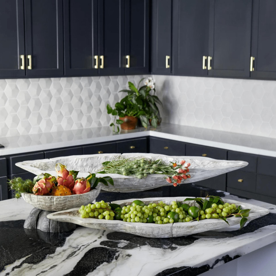 Navarro whitewashed Ardu wood decorative trays on a marble counter, filled with fruit and greenery.