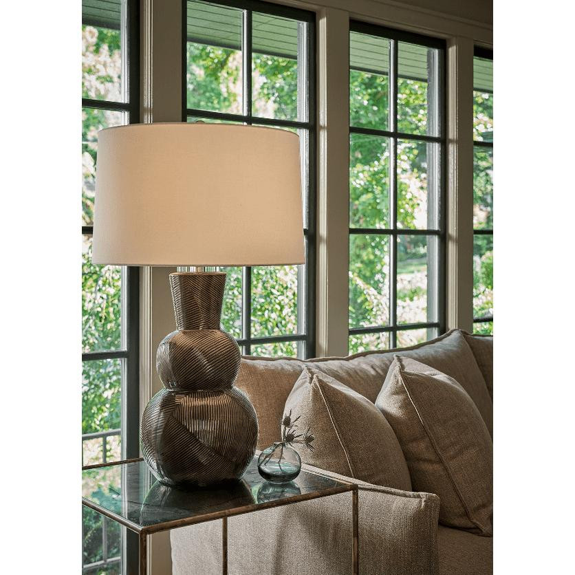 Hugo black ceramic table lamp with a textured base and linen shade on a glass side table.