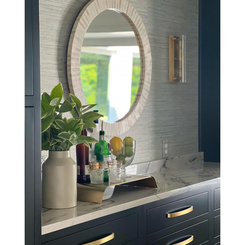 Round multitone bone tile mirror with slender striping, reflecting a coastal look.