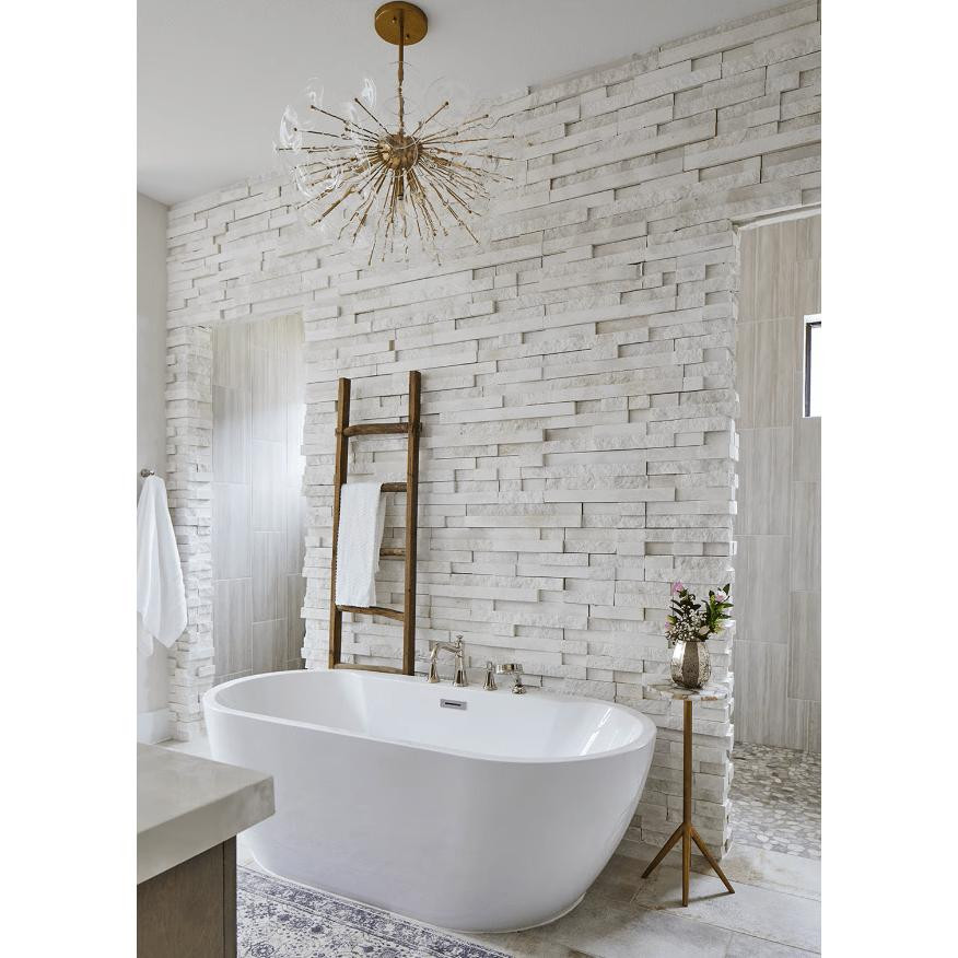 Poppy semi-flush mount light with natural brass rods and undulating clear glass discs over a white bathtub.