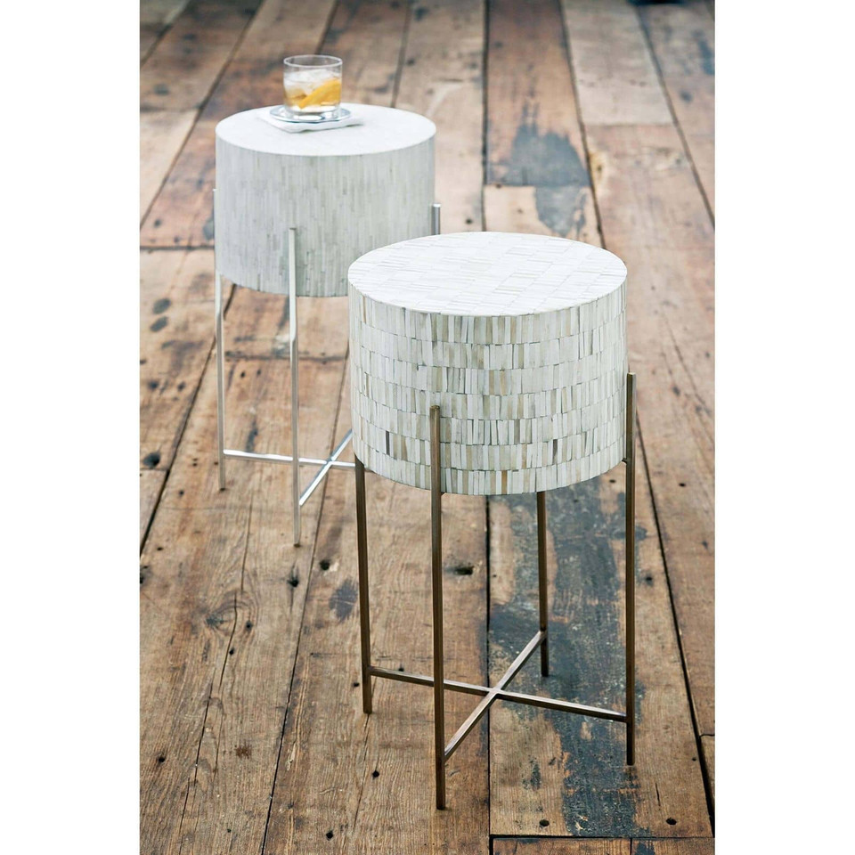Bone drum table with intricate inlaid bone top and antiqued brass legs on a wooden floor.