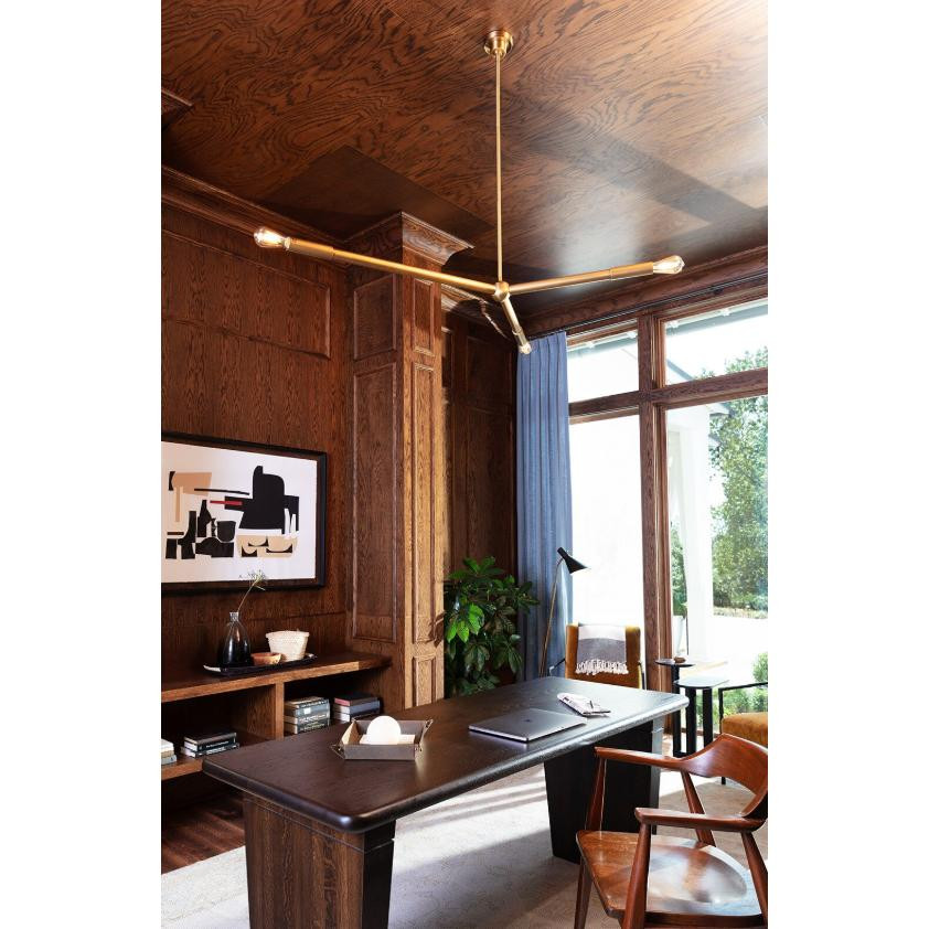 Talon Chandelier in natural brass with three adjustable arms, illuminating a modern home office.