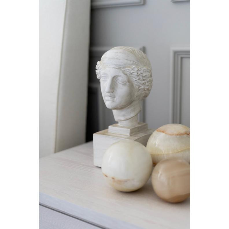 Polished natural jade spheres in varying cream and beige tones next to a white classical bust.