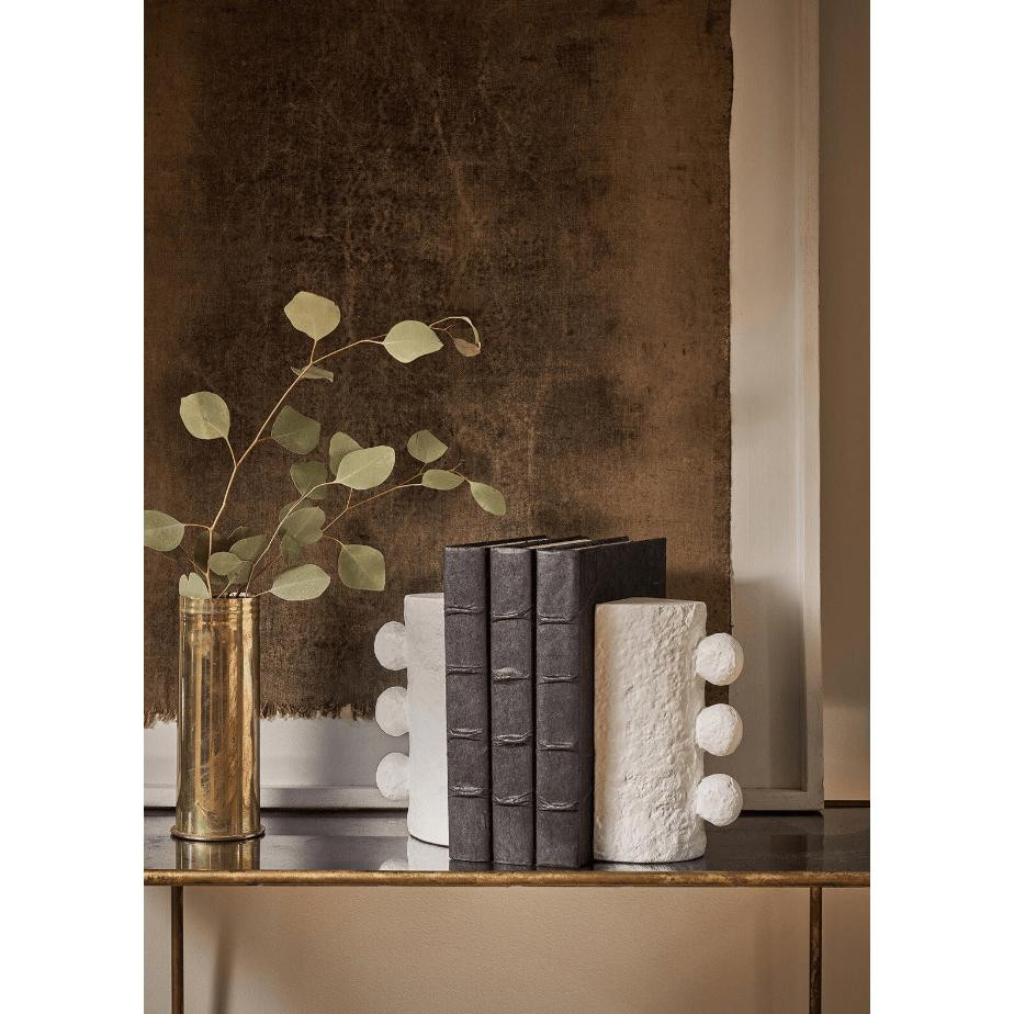 White Sanya Bookends, cast metal with paper mache texture, holding dark books on a console table.