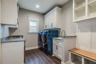 Custom built ins laundry room with closed cabinetry and integrated appliances
