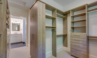 Custom closet built-ins with open shelving, drawers, upper storage, and hanging sections