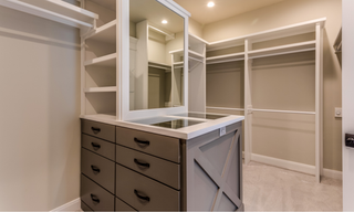 Custom closet with built-in makeup vanity, drawers, shelving, cabinetry, and hanging storage