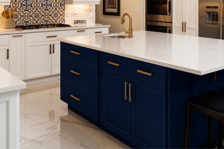 Custom kitchen island with deep navy blue shaker panels and gold hardware for a bold designer focal point