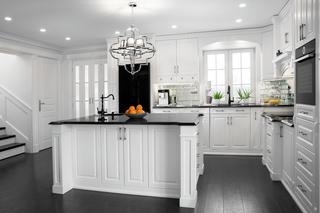 Custom kitchen island with double doors and white raised panels paired with black countertops for dramatic contrast