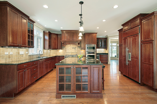 Custom kitchen island with real wood cabinetry and glass panel doors for display storage and elevated design