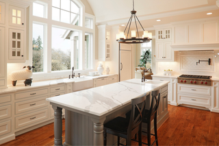Custom kitchen island with grey fluted panels and corbels topped with quartz countertop paired with white cabinetry