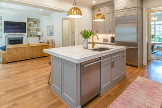 Custom kitchen island with grey shaker panels and dishwasher built into the island for streamlined cleanup