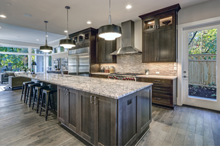 Custom kitchen island with grey wood shaker panels and matching cabinetry paired with marble countertops