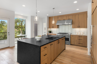Custom kitchen island with light wood slab panels and black countertop for bold contrast modern design