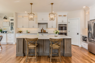 Custom kitchen island with wood wash stain and brown shaker panels paired with white cabinetry for a balanced look