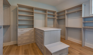 Custom U-shaped walk-in closet with center island, wall-to-wall shelving, drawers, and hanging storage