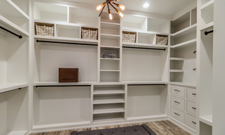 White custom walk-in closet built-in storage system with cabinets, shelving, drawers, and hanging space
