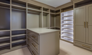 Custom walk-in closet storage system with center island, drawers, shelves, and hanging sections