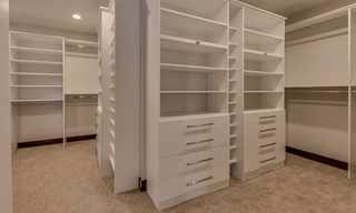 Custom white walk-in closet organization system with shelves, drawers, and hanging storage