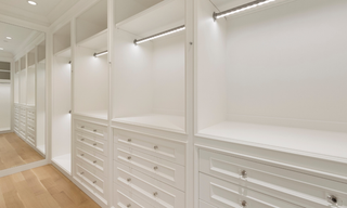 Luxury white custom closet built-ins with drawers, shelving, cabinetry, and hanging sections