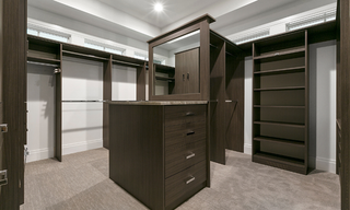 Modern custom closet built-ins with a center island, open shelving, drawers, and hanging storage