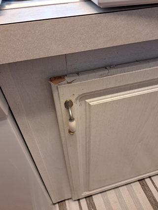 Close-up of chipping cabinet paint before refacing