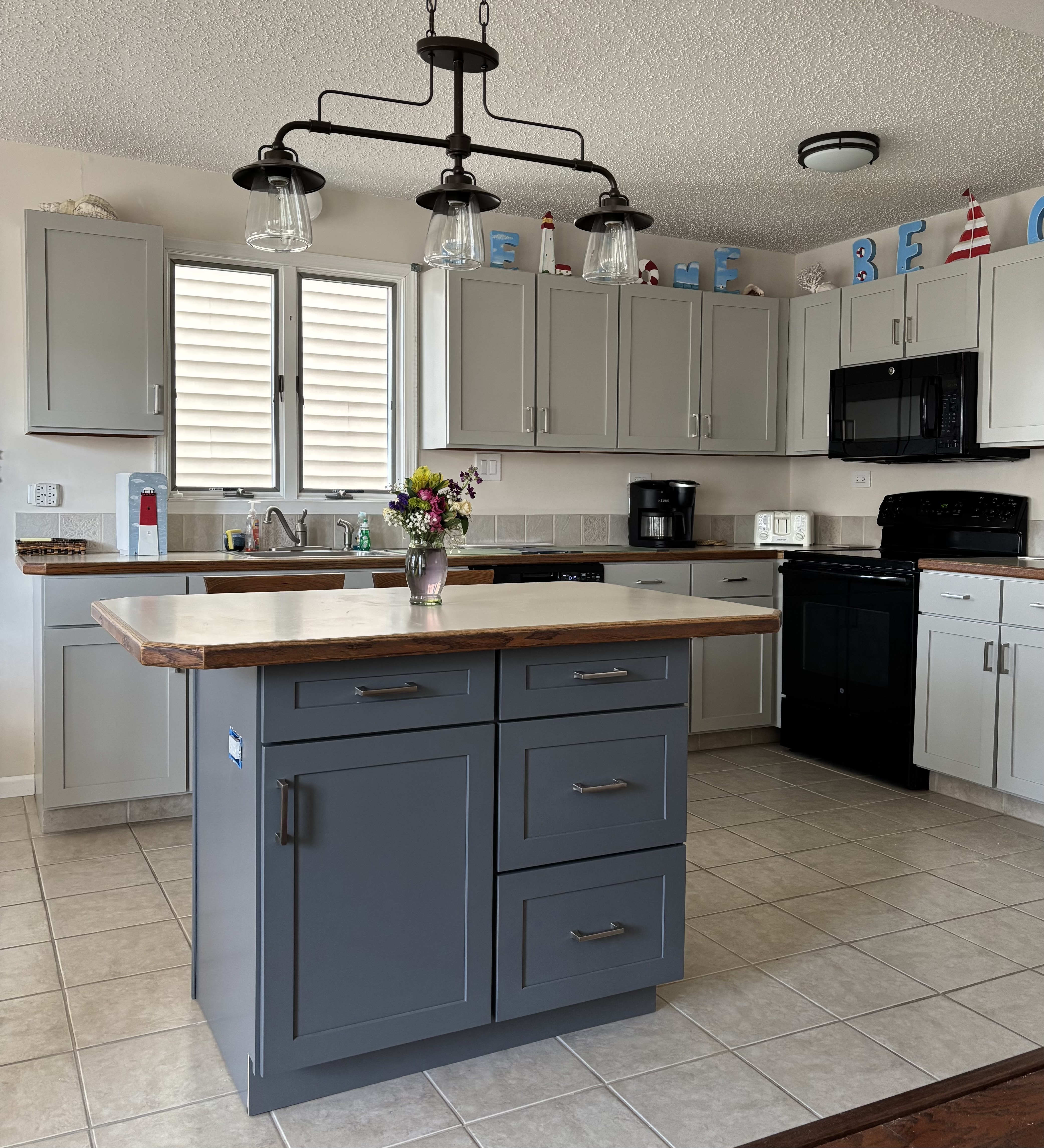 Coastal kitchen remodel featuring painted shaker cabinet doors in Mindful Gray and Midnight Gray with custom cabinet refacing and wood countertops.