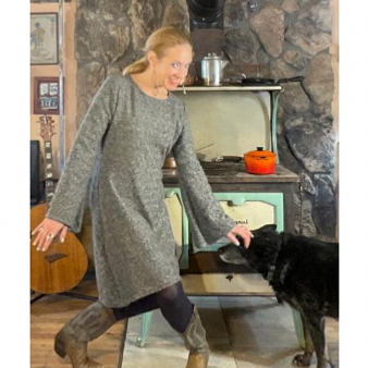 Colorado fashion designer Stephanie Jones wearing a fleece dress in front of a woodstove with her cattle dog