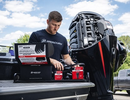 A boater servicing a Mercury outboard engine with genuine Mercury parts