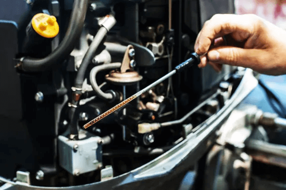 Close-up of a hand checking engine oil dipstick on a boat.