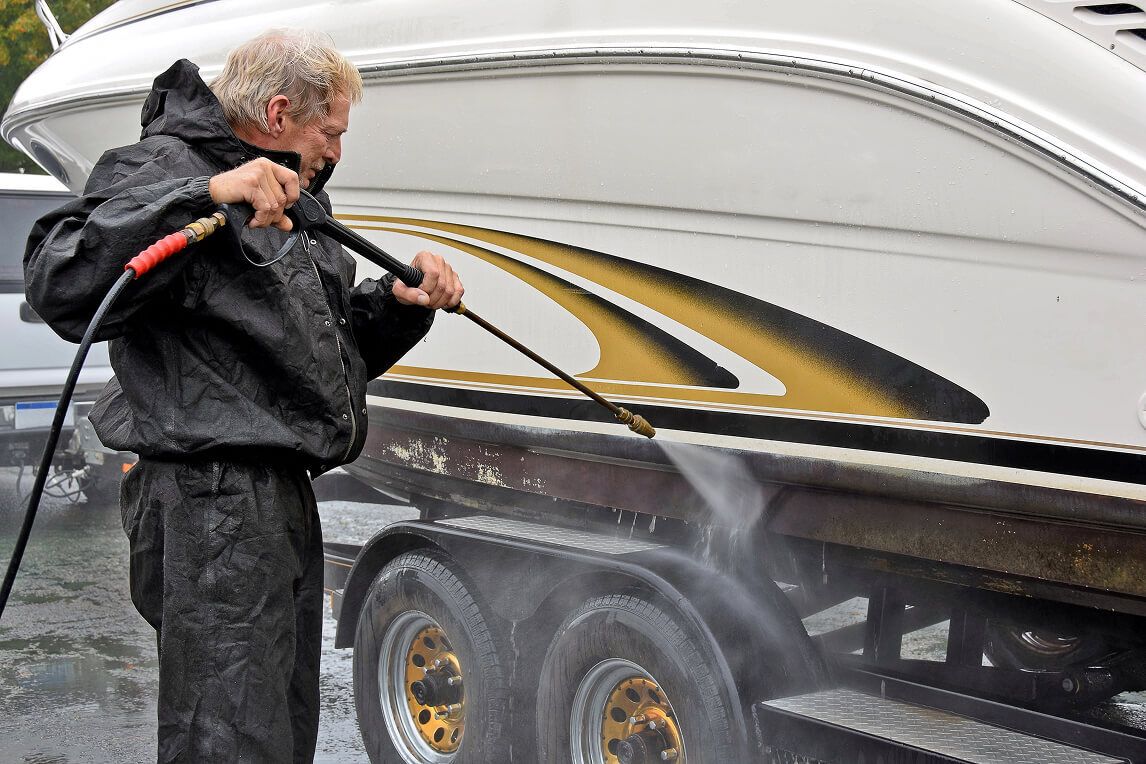 Man power-washing a boat trailer.