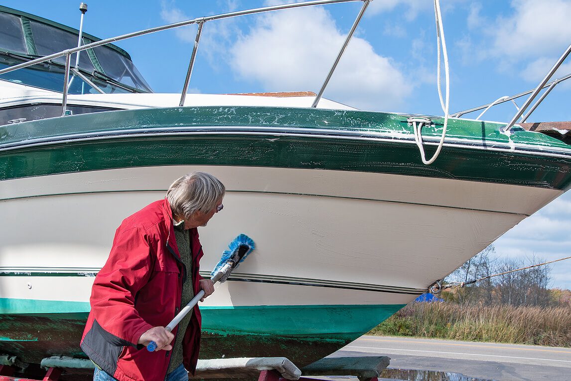 Man drying a boat out of the water with a microfiber cloth