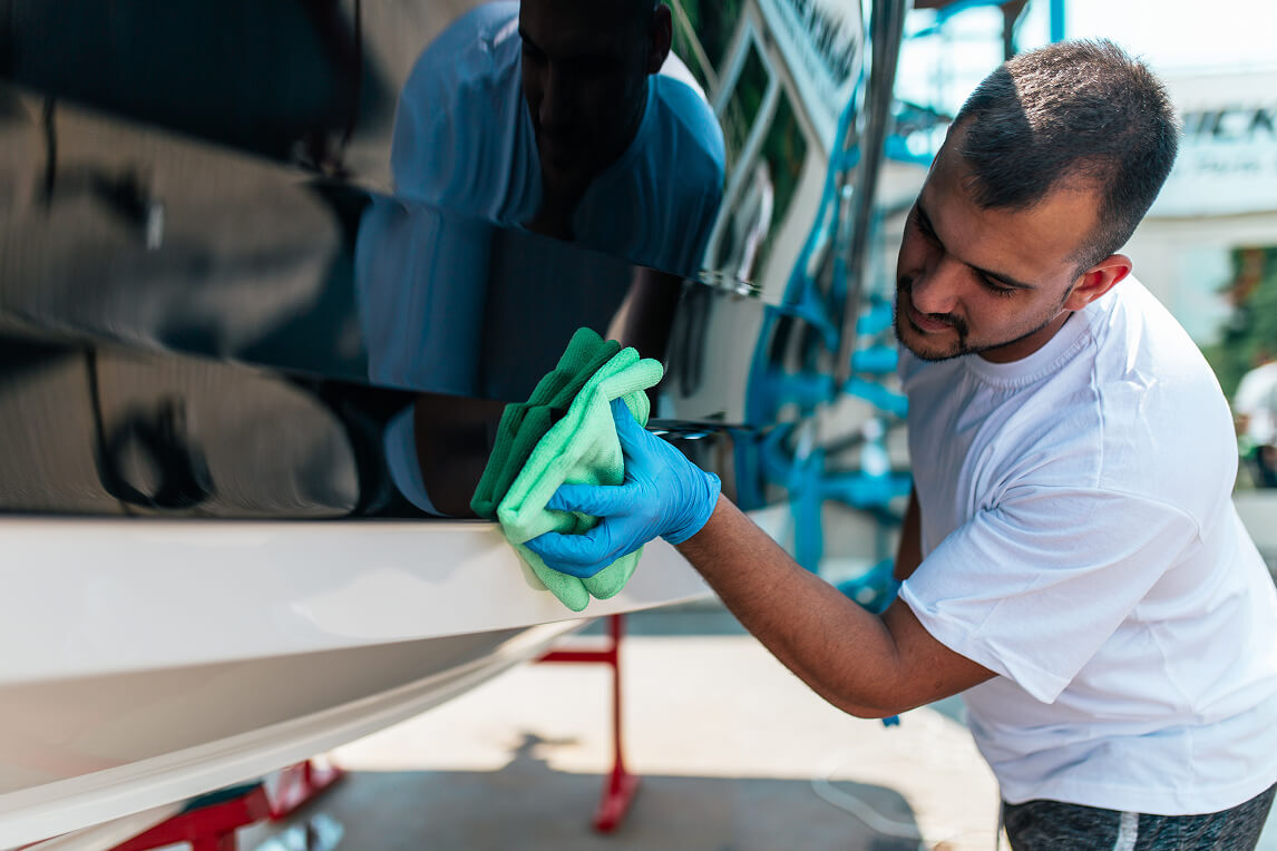 Man cleaning boat with gloves and a microfiber cloth