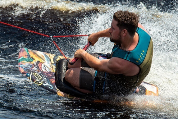 Man carving on kneeboard while being towed