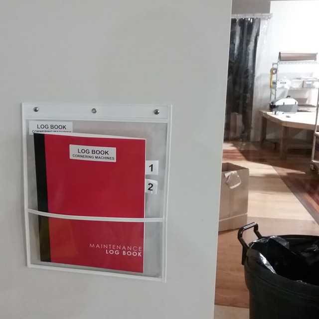 Double-pocket document holder mounted on wall holding maintenance log book paperwork