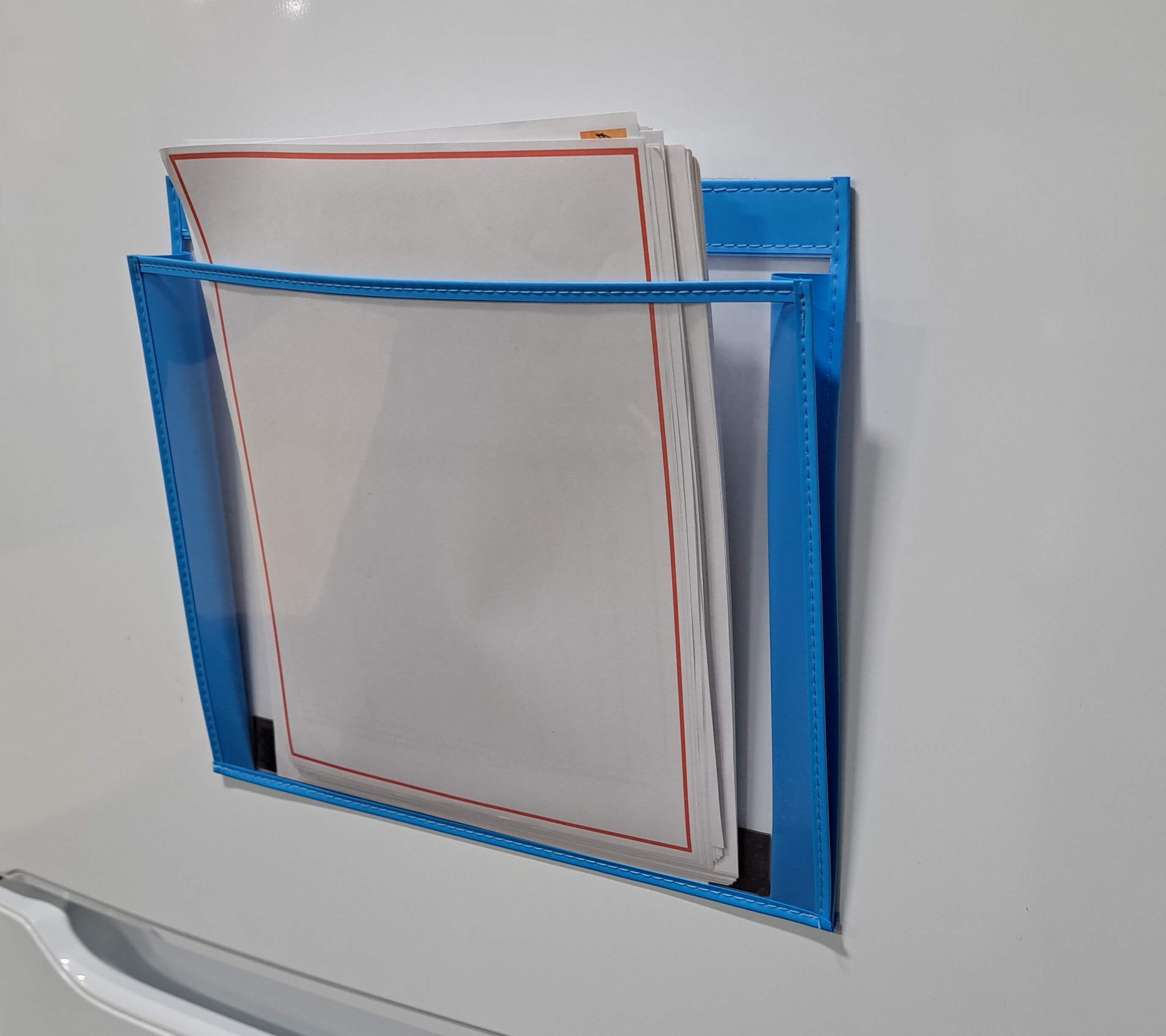 Expandable stitched trim landscape magnetic 12x9 document holder shown holding packet of paper attached to white metal sruface
