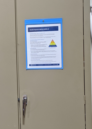 Magnetic stitched sky blue color trim sign holder with chemcial safety information attached to an industrial steel storage cabinet