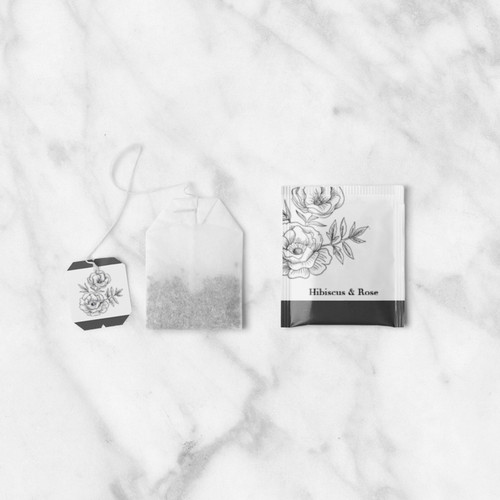 Bag of hibiscus and rose tea unwrapped, with a wrapped one to its right.
