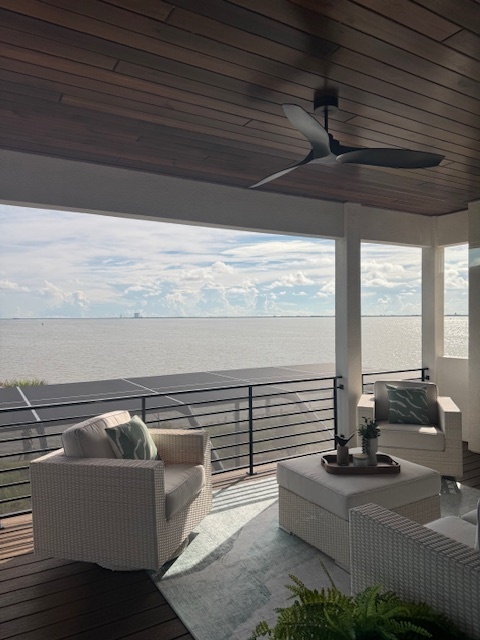 covered deck with a modern ceiling fan and white deck furniture