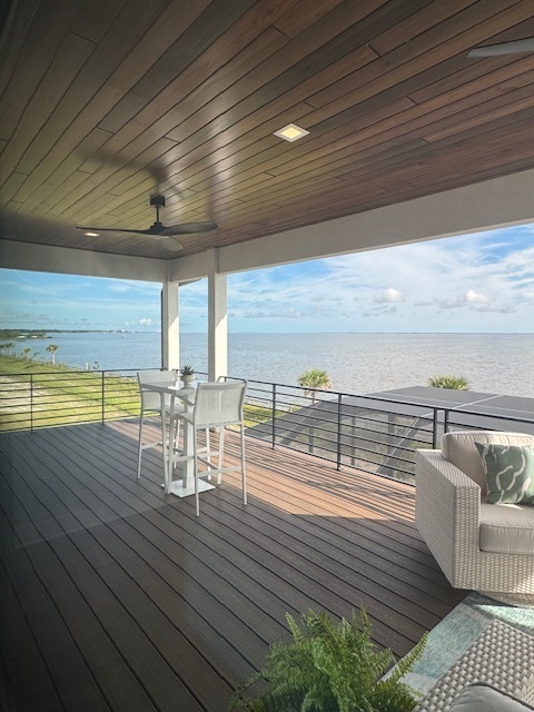 covered deck with modern ceiling fans and a white bar height table with two chairs